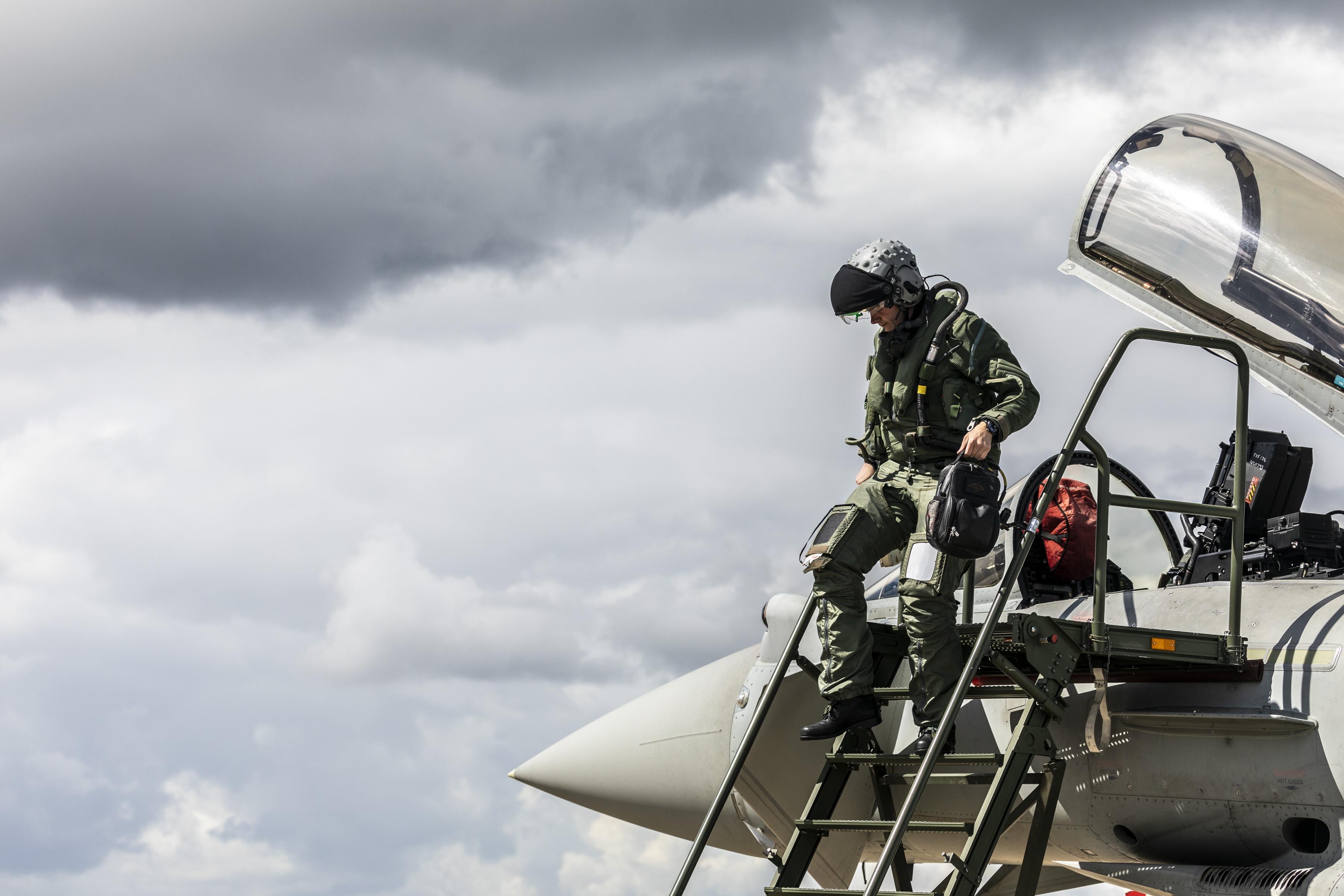 Image shows RAF aviators exiting the cockpit of a Typhoon aircraft on the airfield.